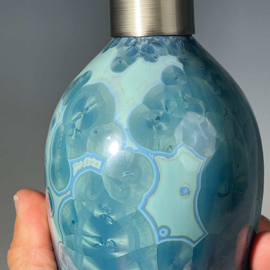 close up of a unique art soap dispenser by Hong Rubinstein in an ocean hued sparkling refractive  macro crystalline glaze