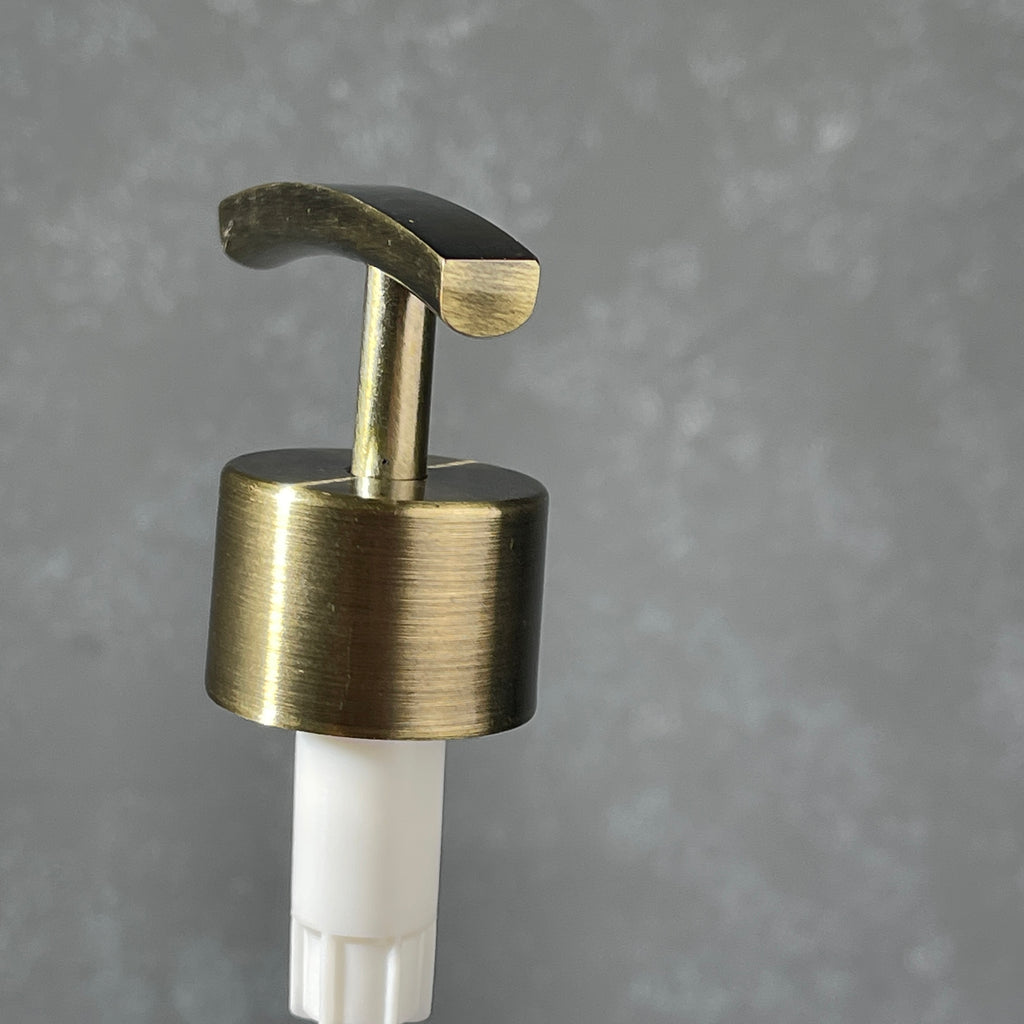 Brass pump dispenser on a gray background