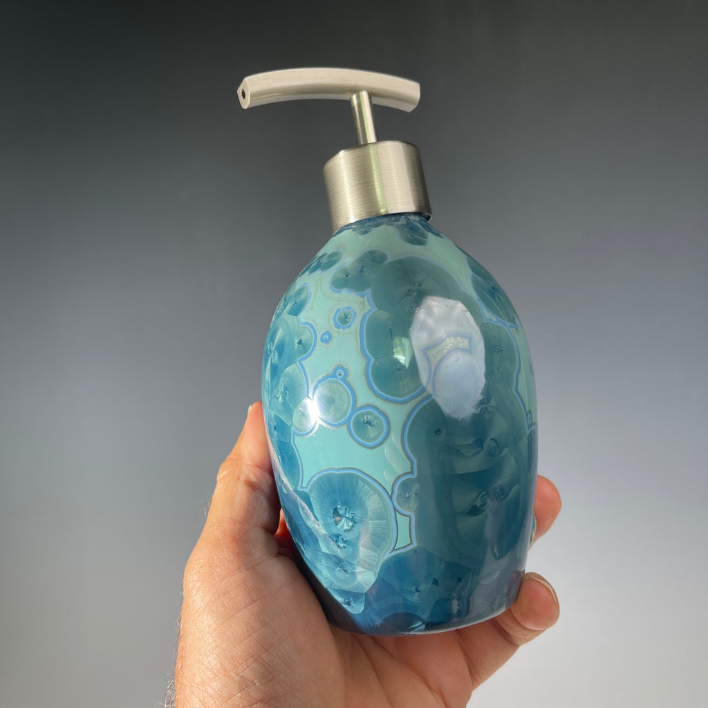close up of a unique art soap dispenser by Hong Rubinstein in an ocean hued sparkling refractive  macro crystalline glaze