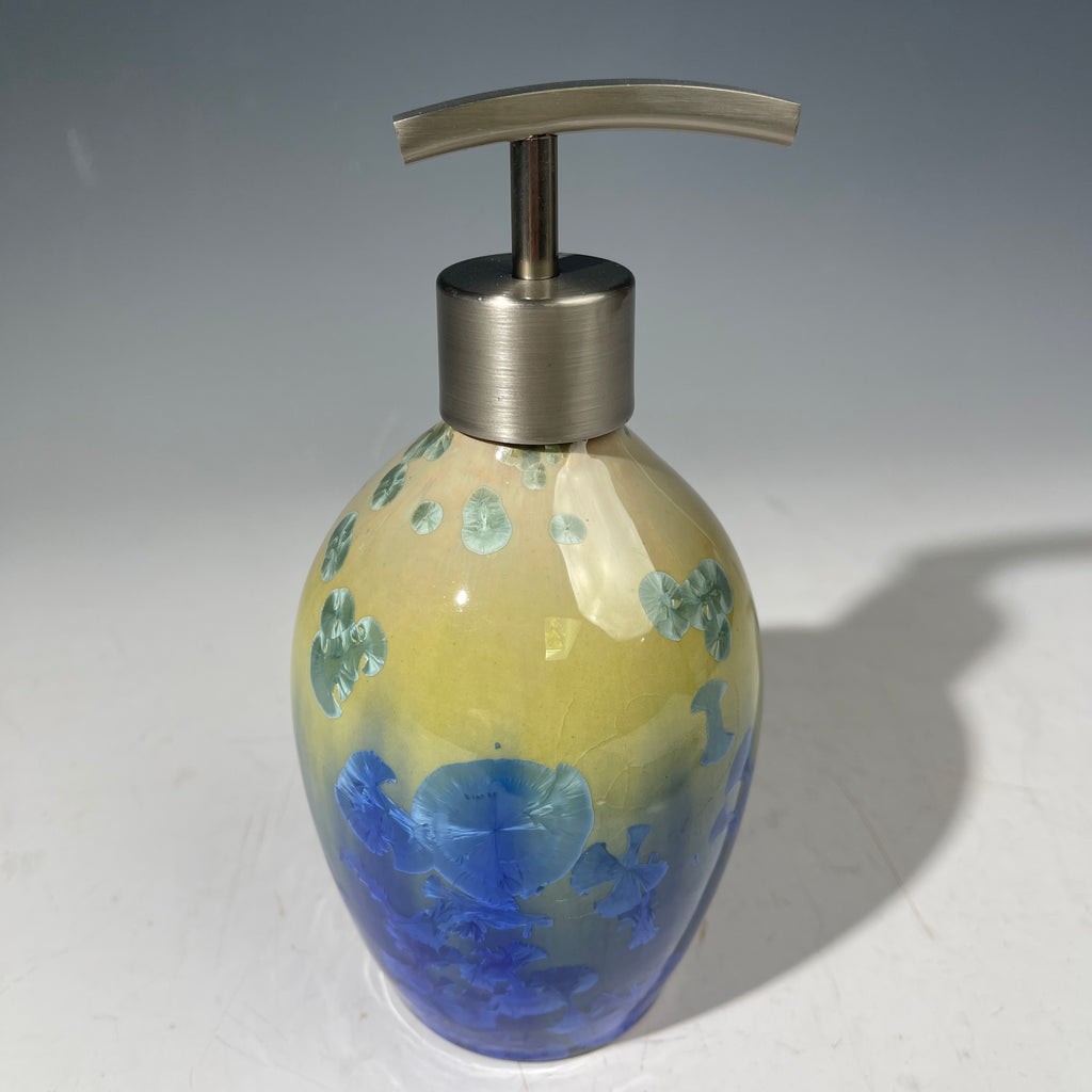A chartreuse to cobalt crystalline glazed soap dispenser by the artist Hong Rubinstein against a gradient gray background