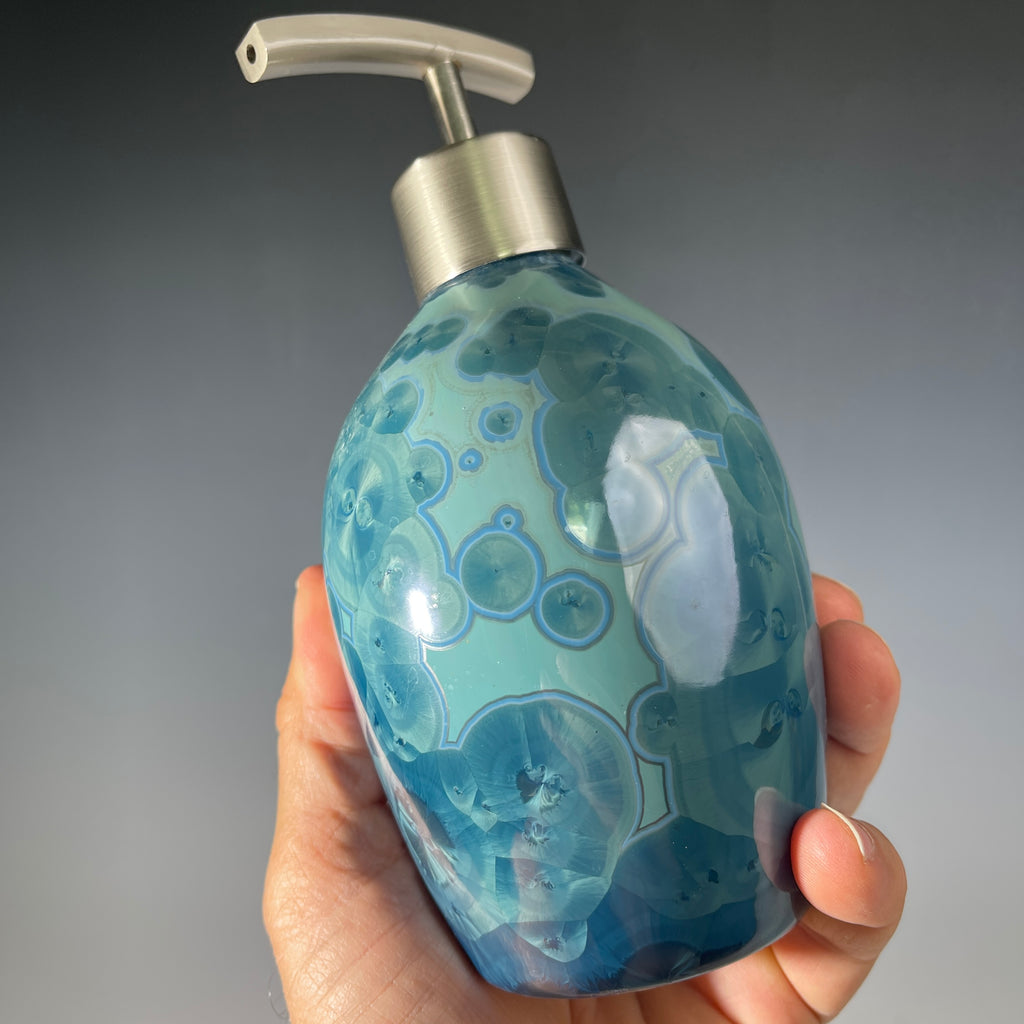 close up of a unique art soap dispenser by Hong Rubinstein in an ocean hued sparkling refractive  macro crystalline glaze