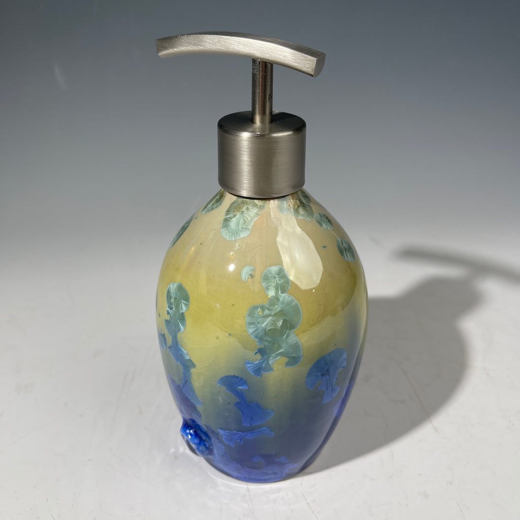 A chartreuse to cobalt crystalline glazed soap dispenser by the artist Hong Rubinstein against a gradient gray background