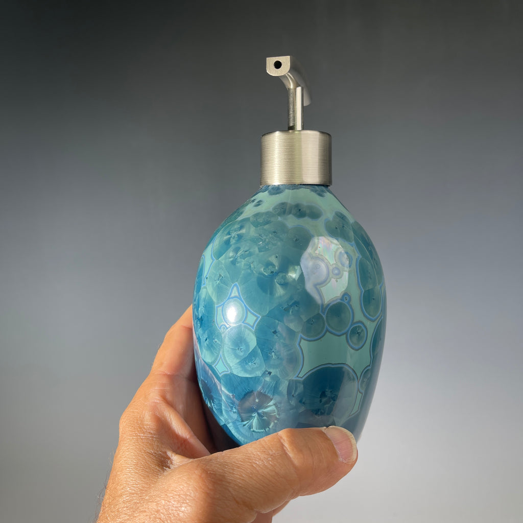 close up of a unique art soap dispenser by Hong Rubinstein in an ocean hued sparkling refractive  macro crystalline glaze