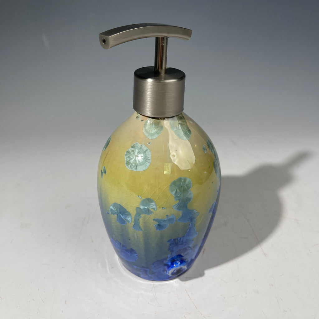A chartreuse to cobalt crystalline glazed soap dispenser by the artist Hong Rubinstein against a gradient gray background