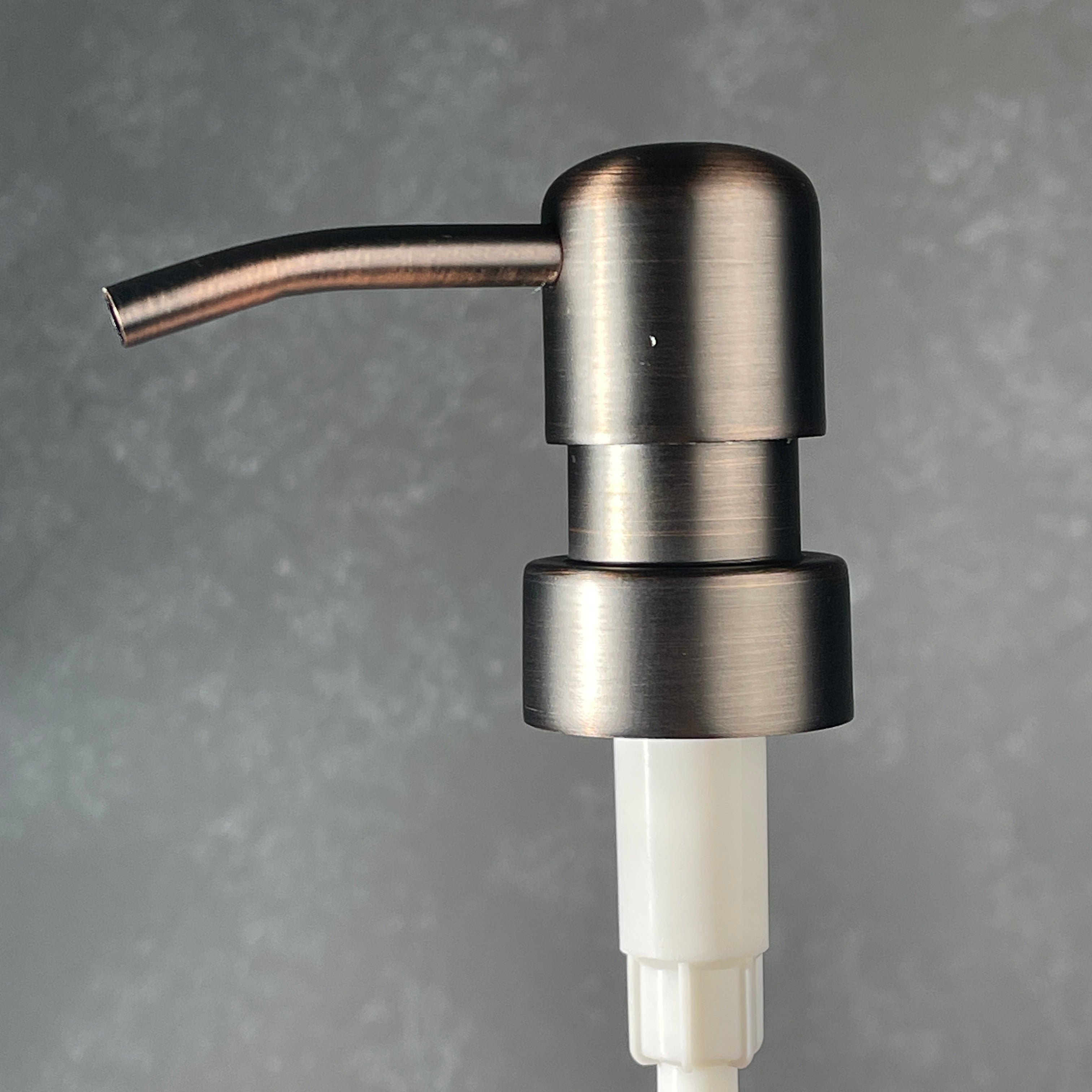 Metallic oil rubbed bronze soap dispenser on a gray background