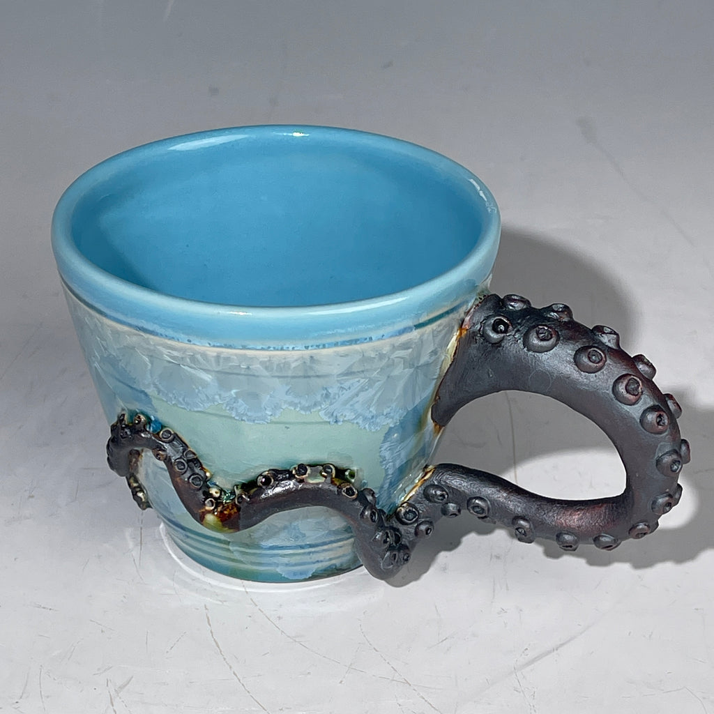 Blue ceramic cup with an octopus handle on a white background