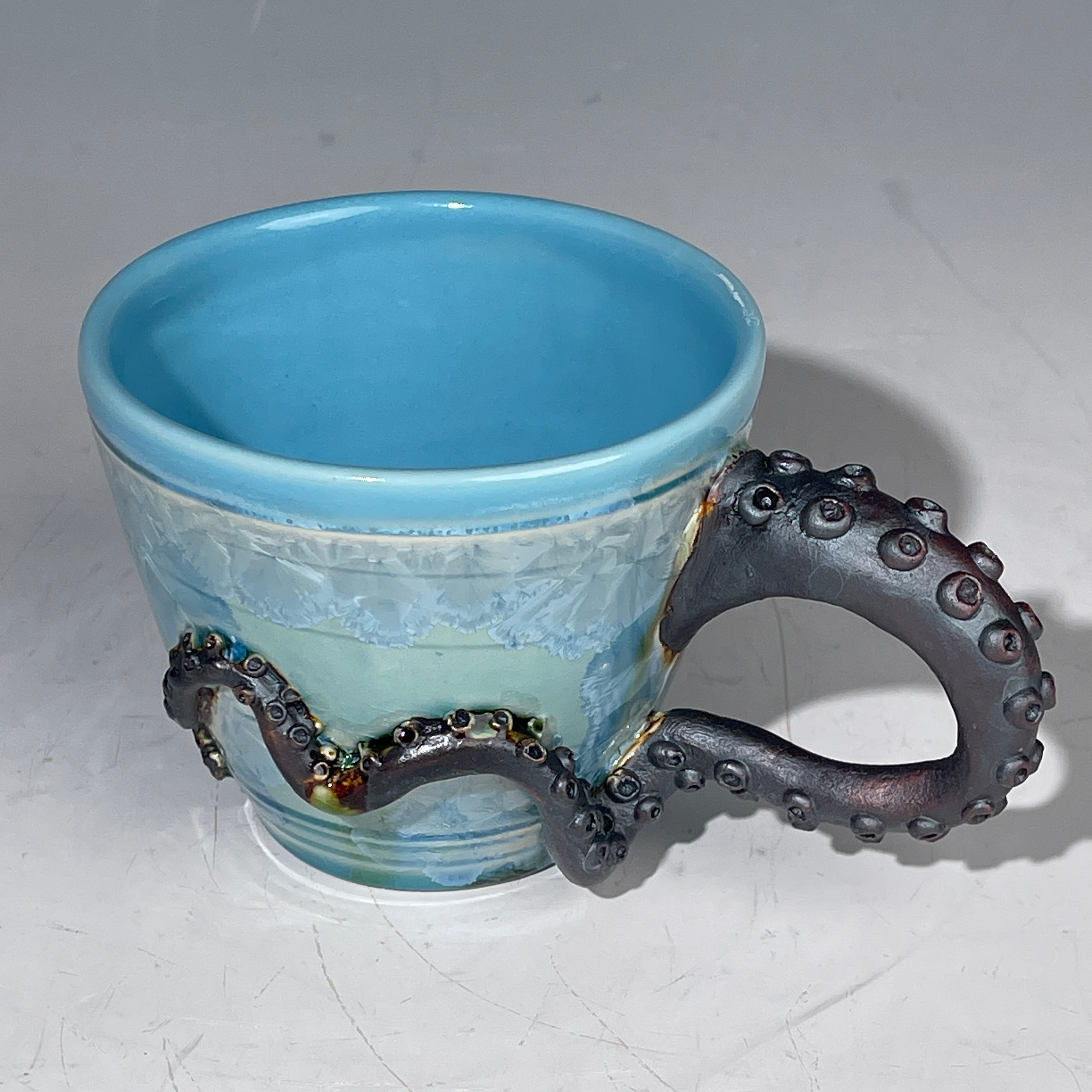 Blue ceramic cup with an octopus handle on a white background