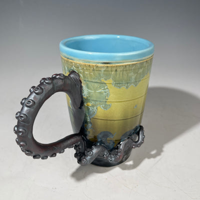Ceramic mug with an octopus handle on a gray background