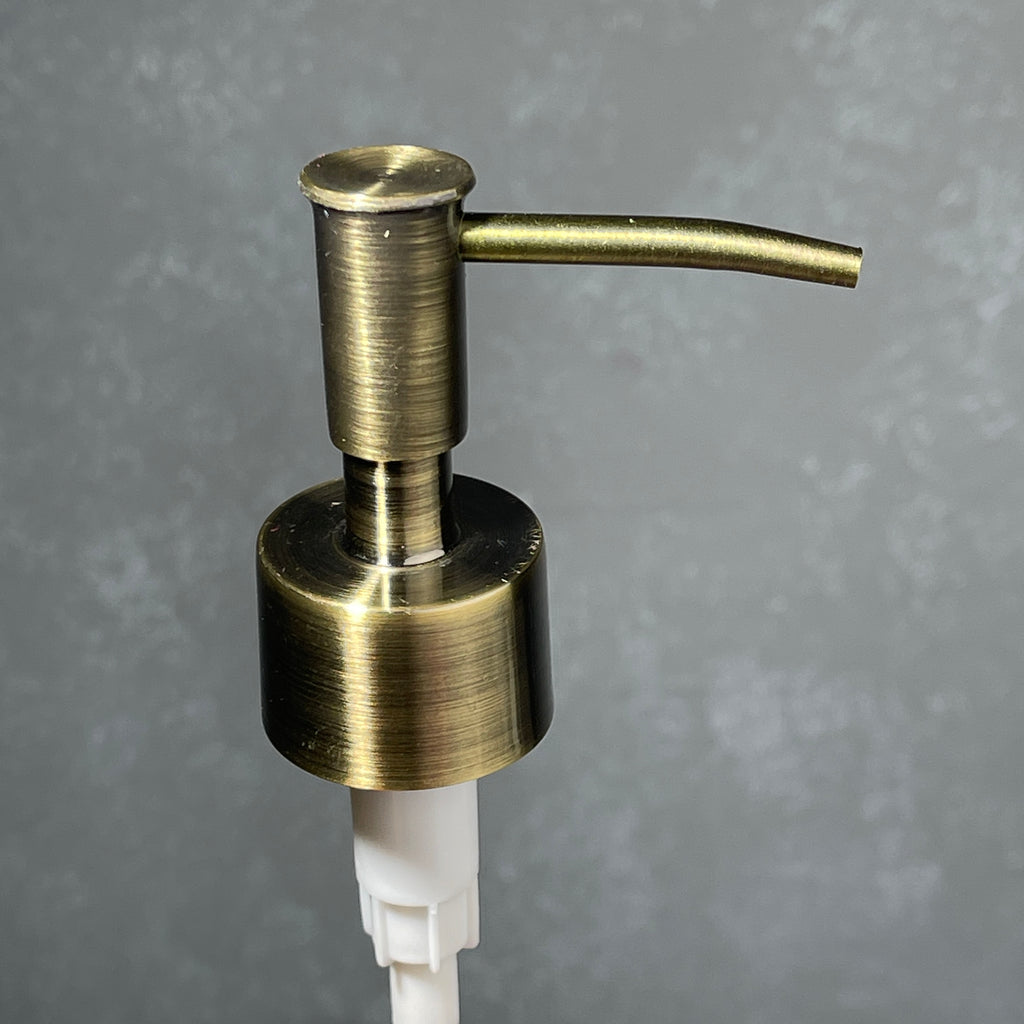 Brass soap dispenser on a gray background