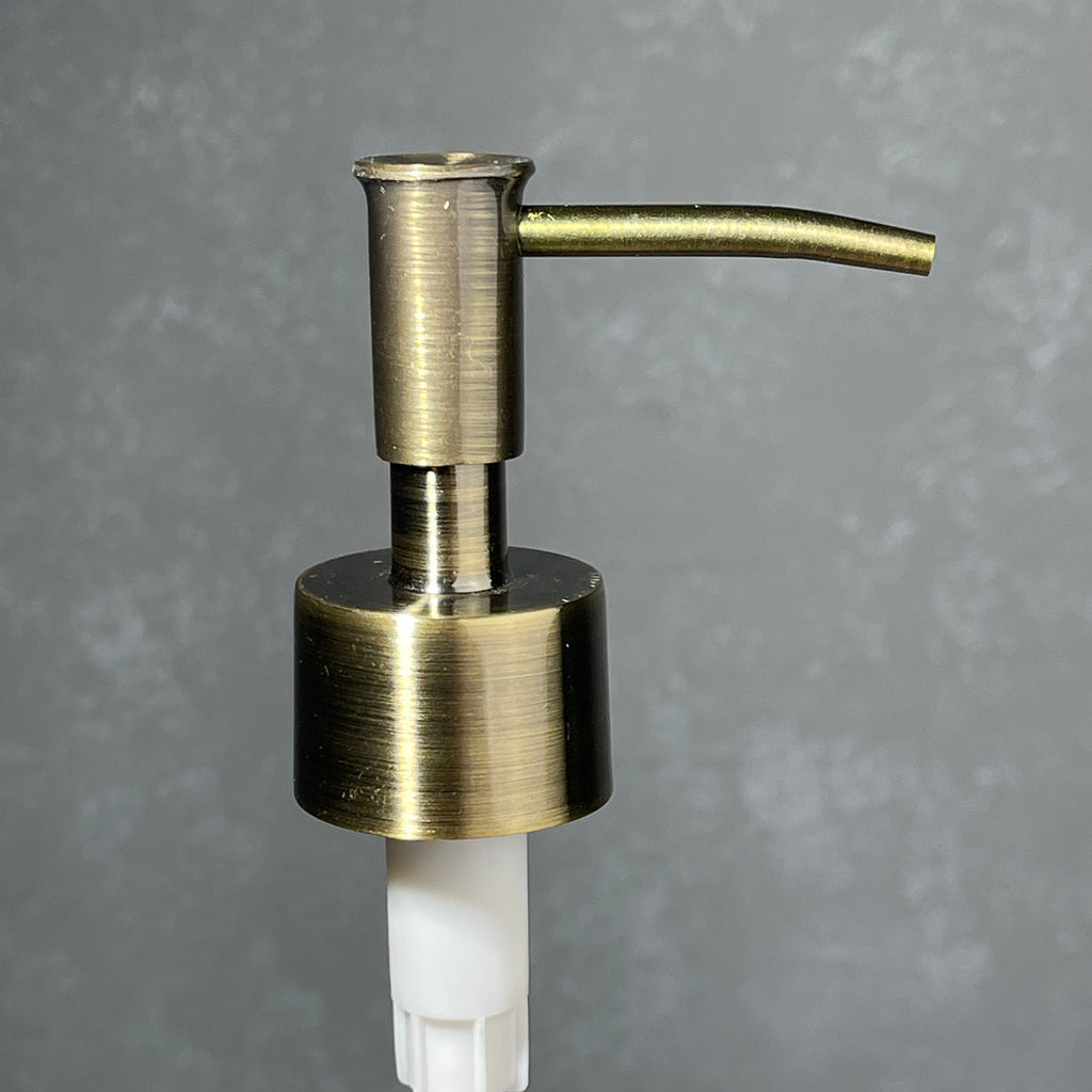 Brass soap dispenser on a gray background
