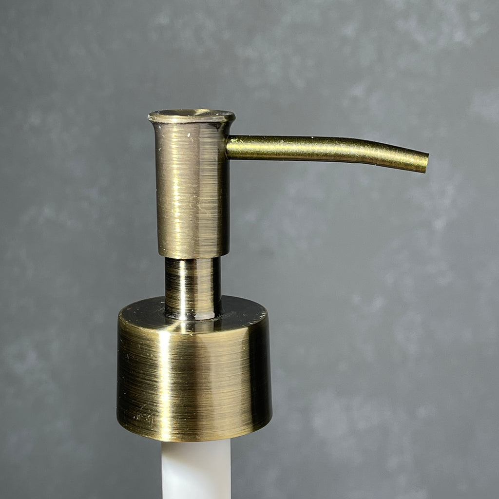 Brass soap dispenser on a gray background