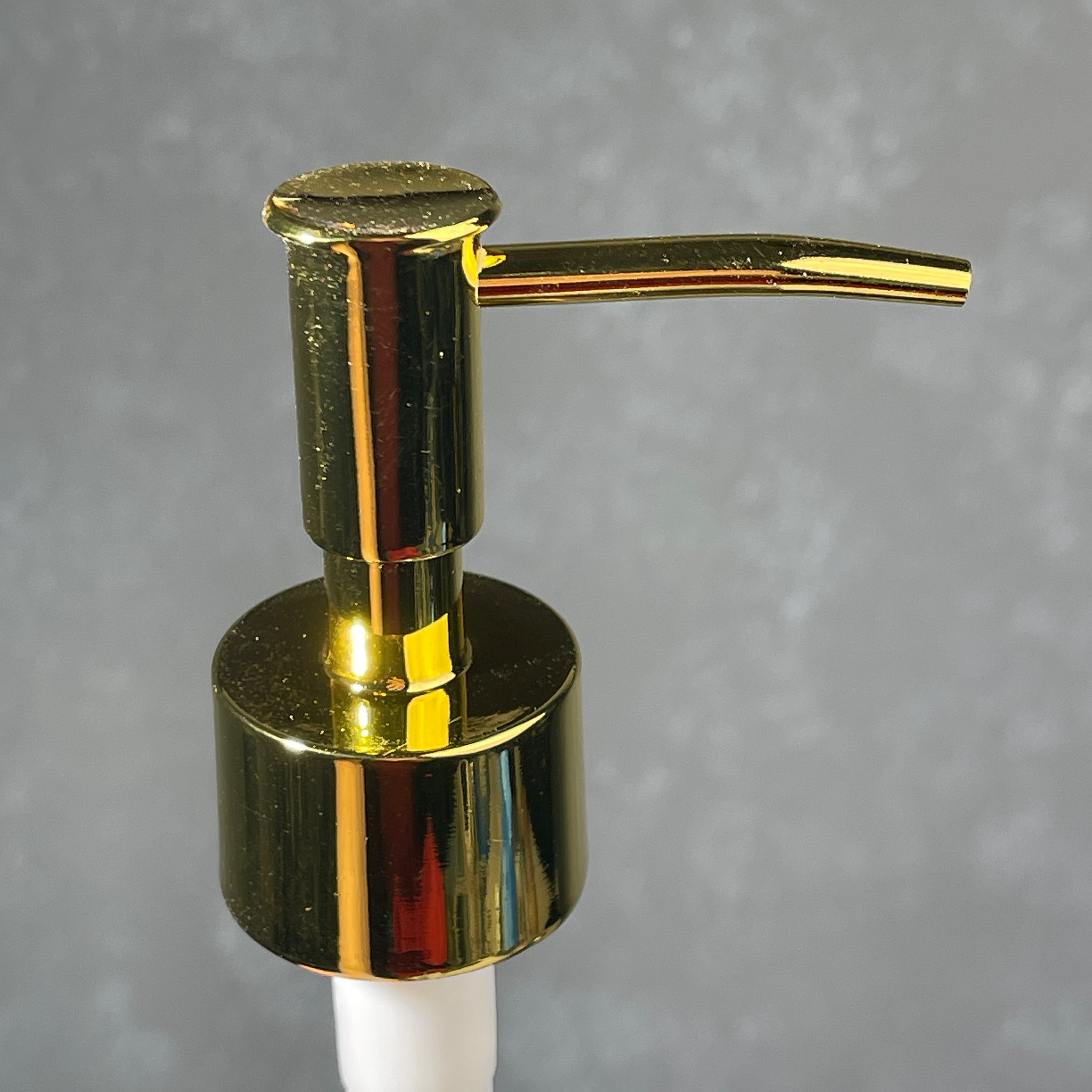 Gold soap dispenser on a gray background