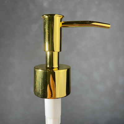 Gold soap dispenser on a gray background